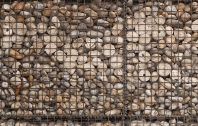 Close view of handmade white ceramic pebbles among beach shingle, impressed with names, initials, shells and patterns.