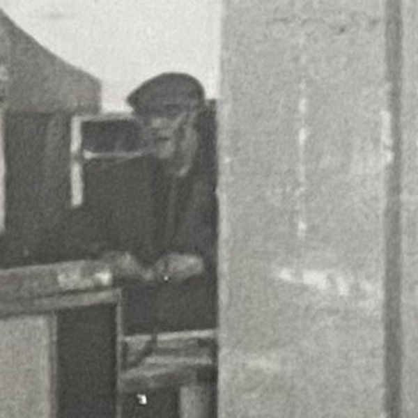 Unidentified man in a flat cap standing at the far end of the room inside V C Jones, Harbour Street, Whitstable