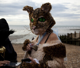 Close-up of a handmade tabby cat mask with green eyes and long whiskers on Whitstable beach